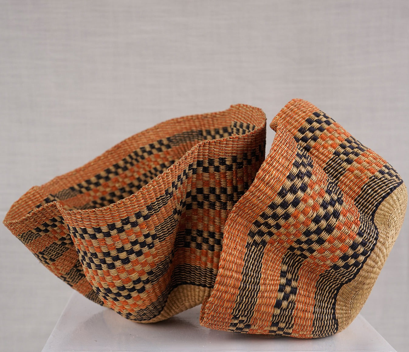Woven basket with a geometric pattern on a light gray background