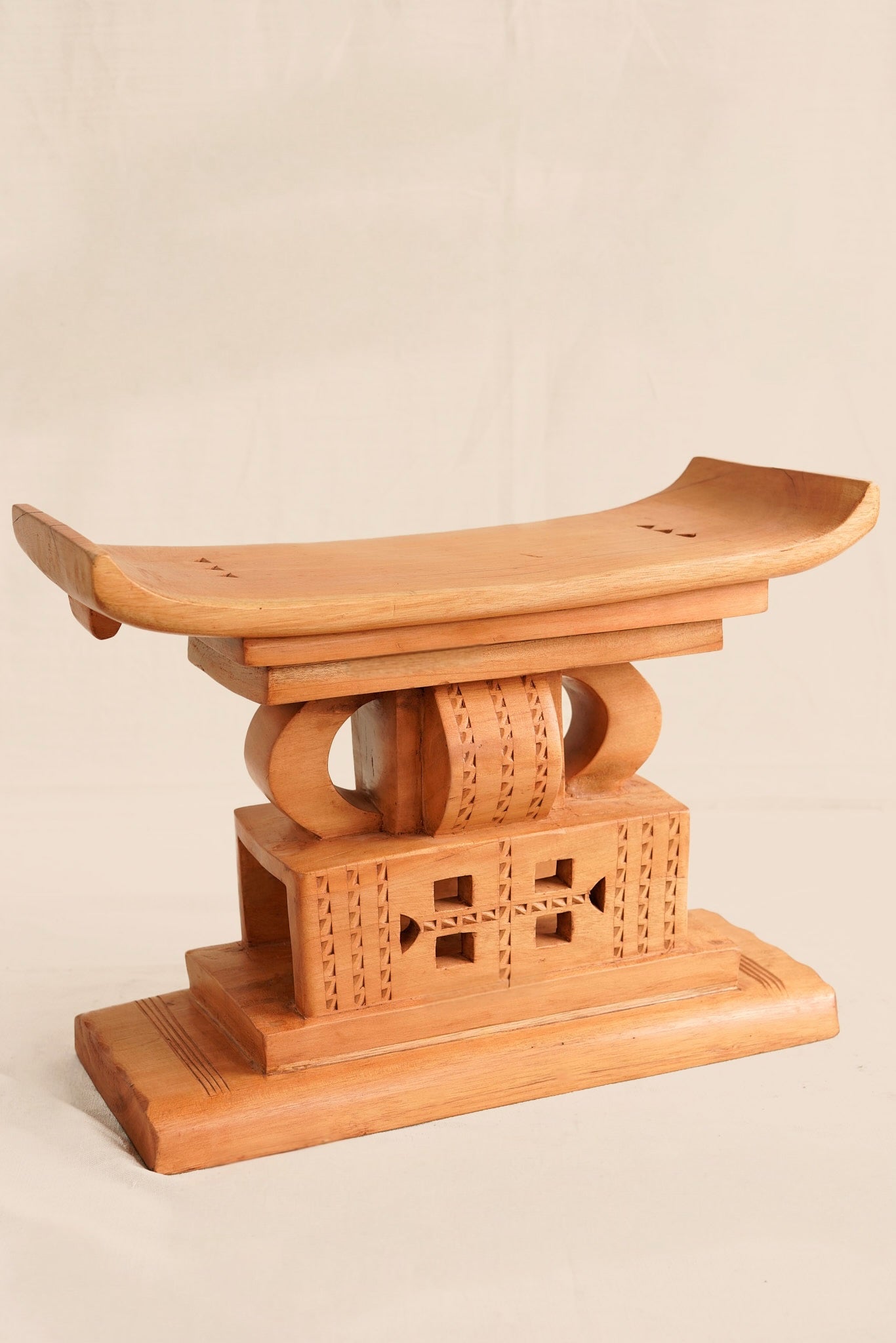 Wooden stool with intricate carvings on a beige background