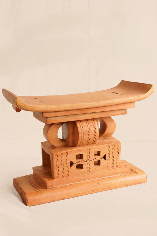 Wooden stool with intricate carvings on a beige background