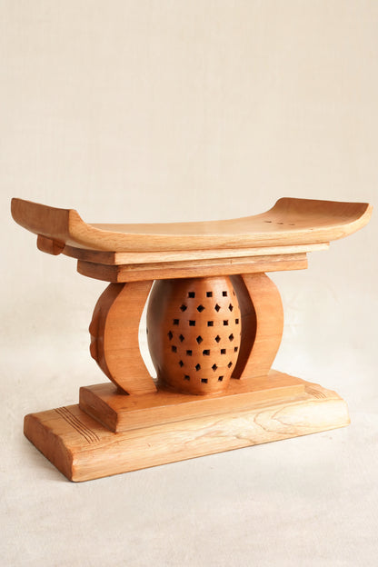 Wooden stool with a spherical seat on a beige background