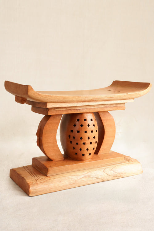 Wooden stool with a spherical seat on a beige background
