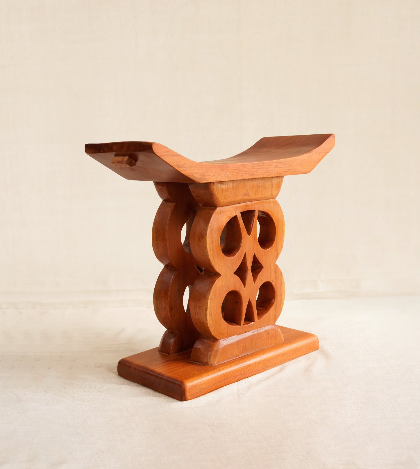 Wooden stool with intricate design on a beige background
