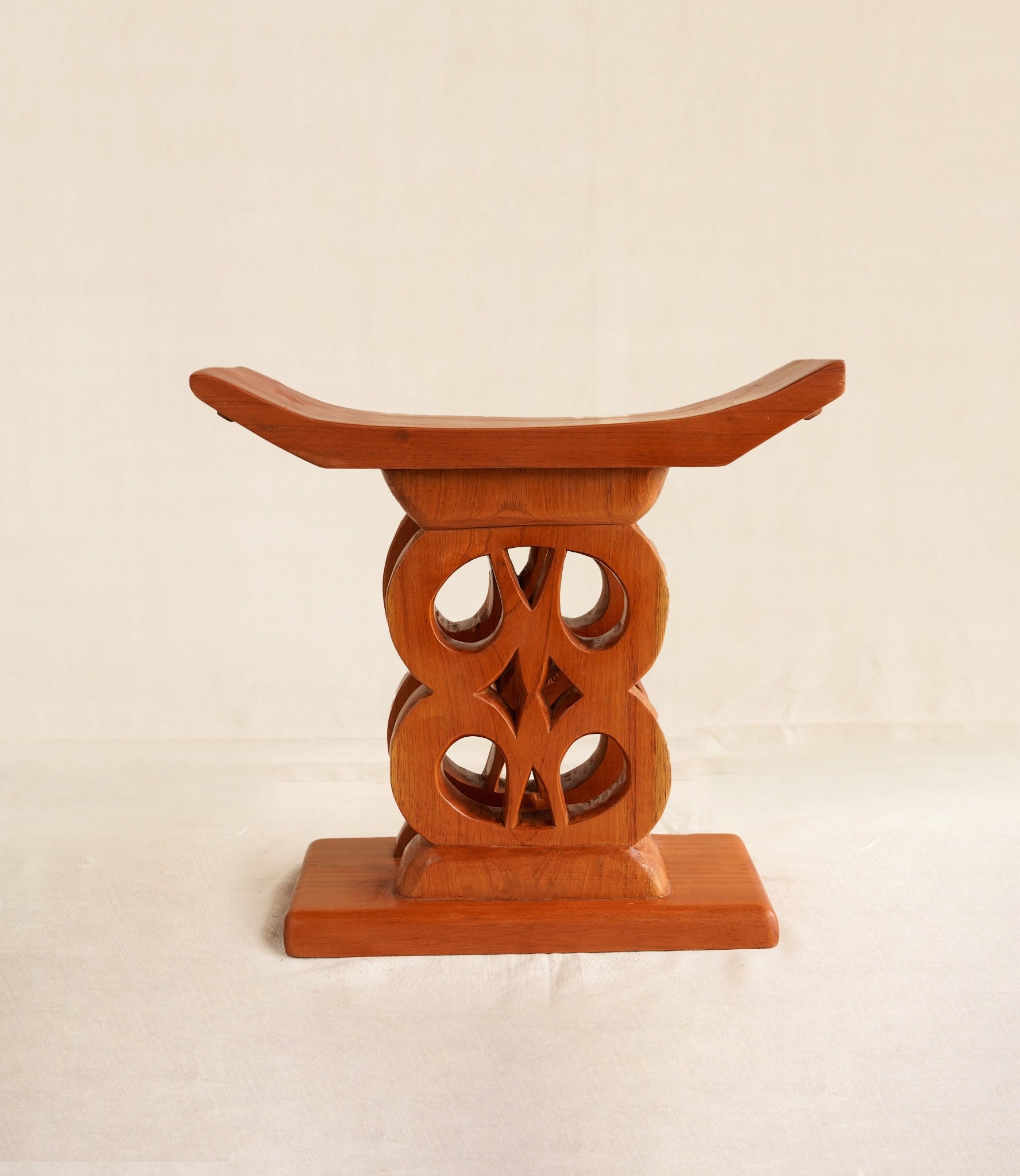 Wooden stool with intricate design on a beige background