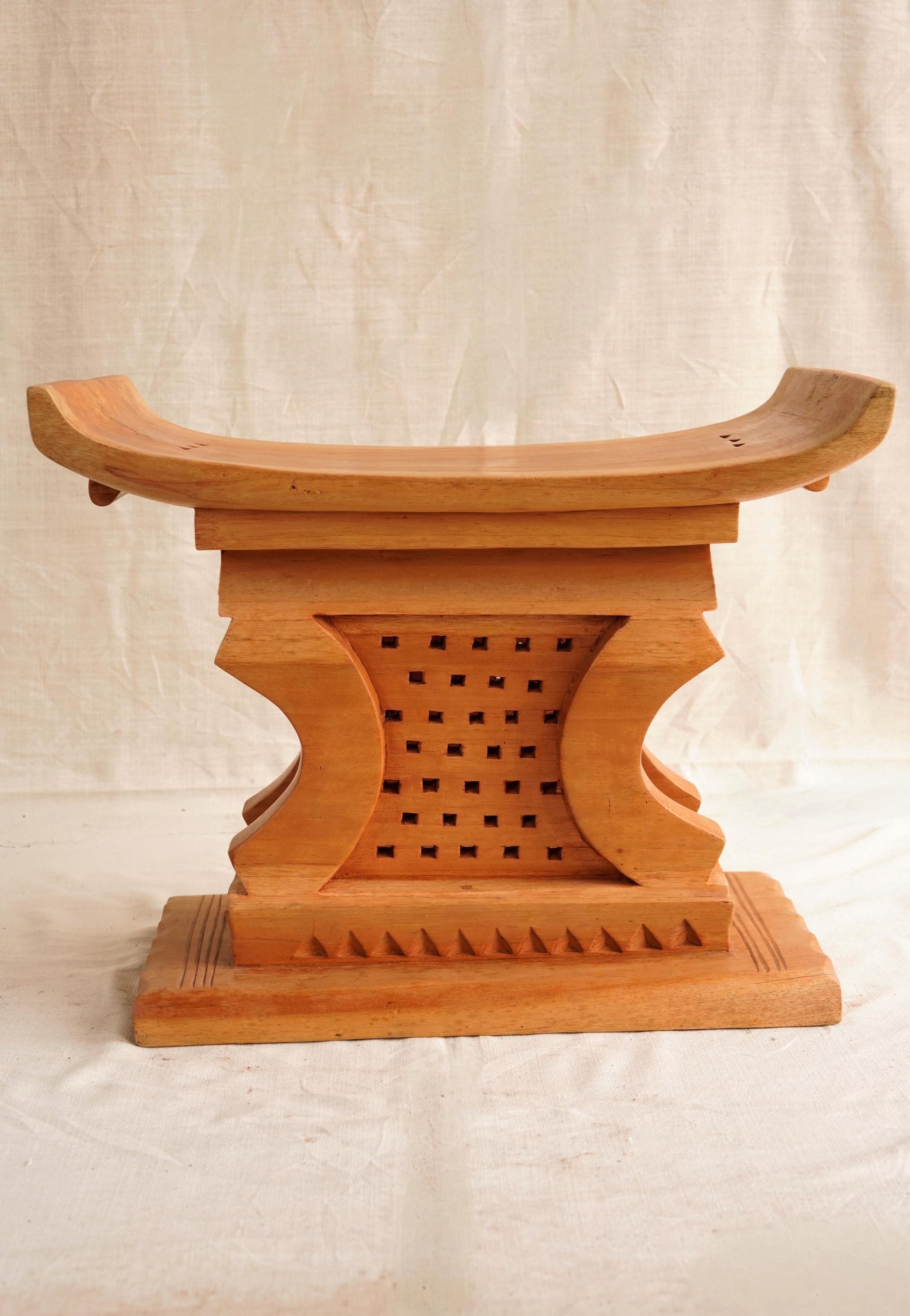 Wooden stool with intricate carvings on a plain background