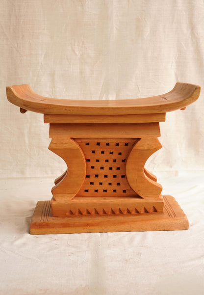 Wooden stool with intricate carvings on a plain background