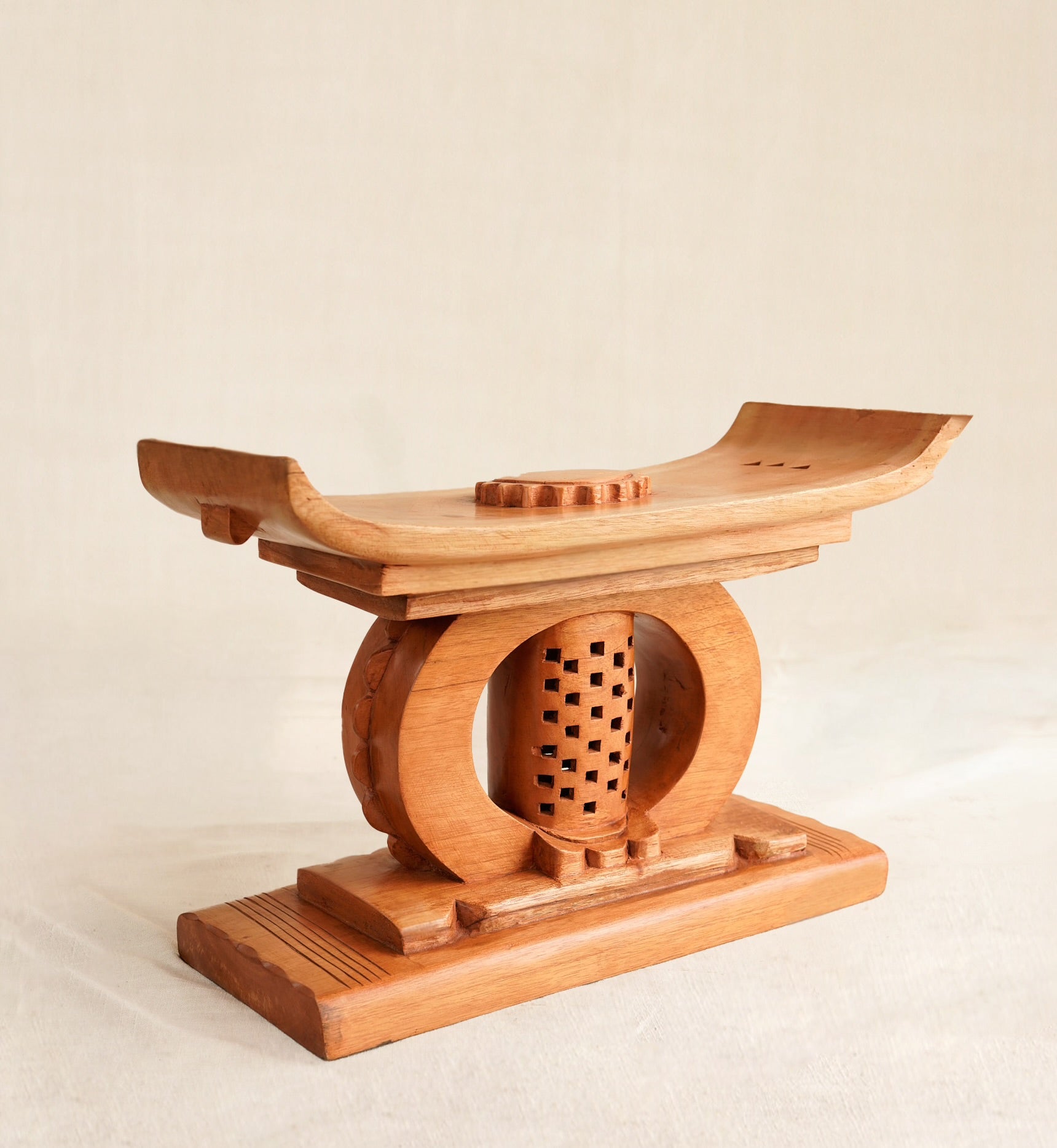 Wooden Ashanti stool with a circular design on a beige background