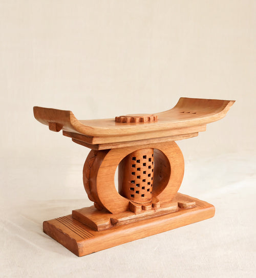 Wooden Ashanti stool with a circular design on a beige background