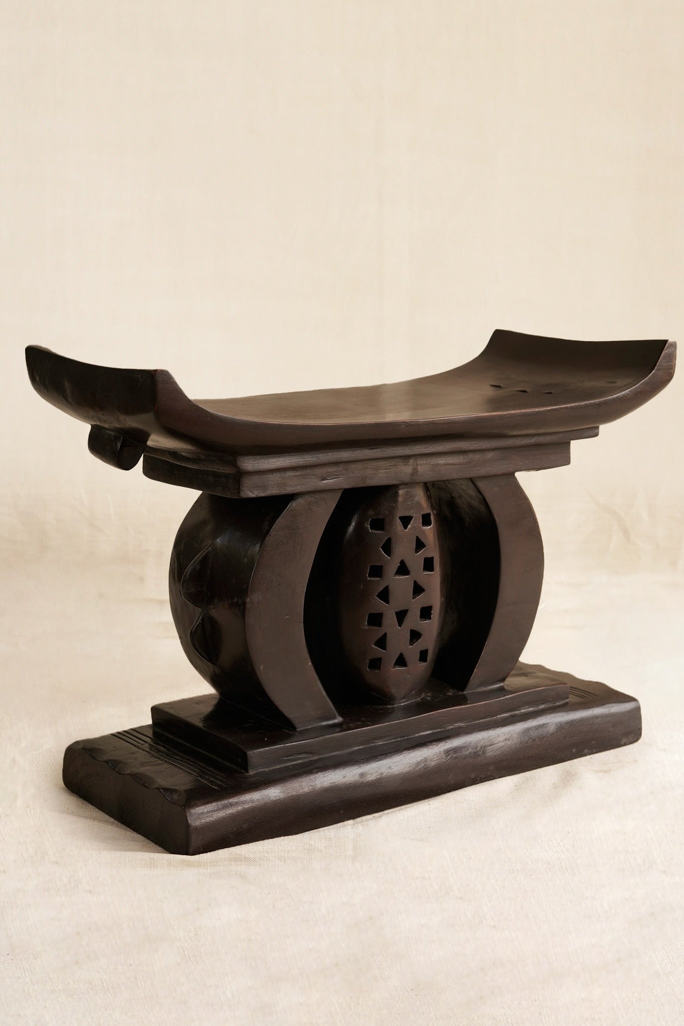 Traditional wooden stool with a curved backrest on a beige background