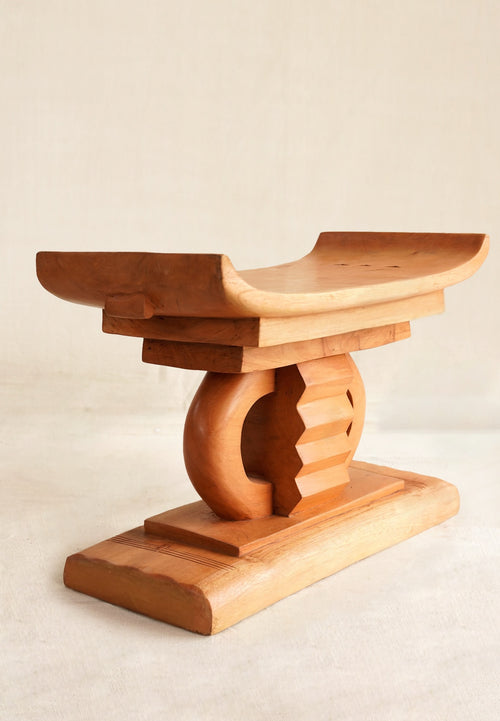 Wooden stool with a curved design on a beige background