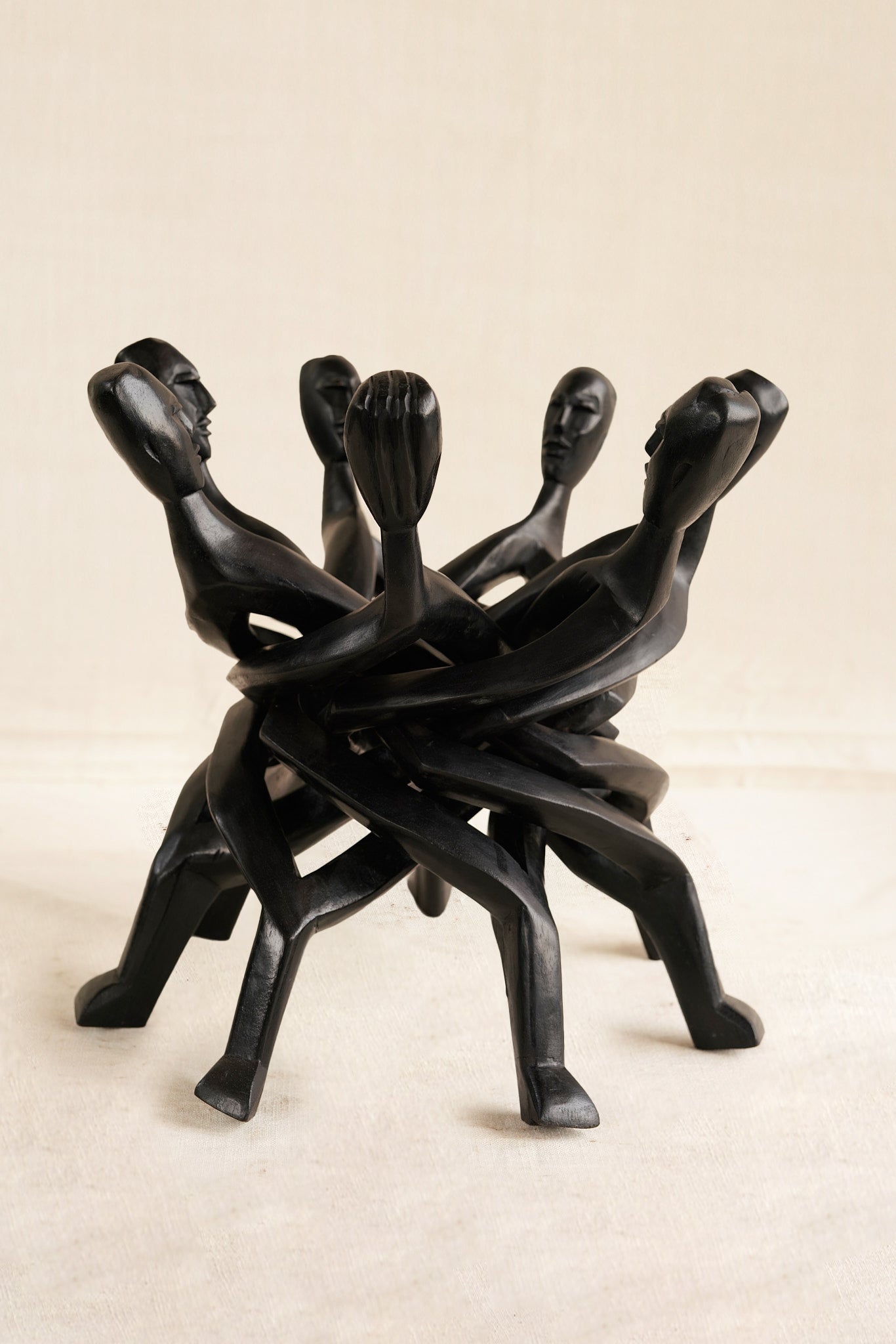 Black abstract sculpture of intertwined figures on a beige background