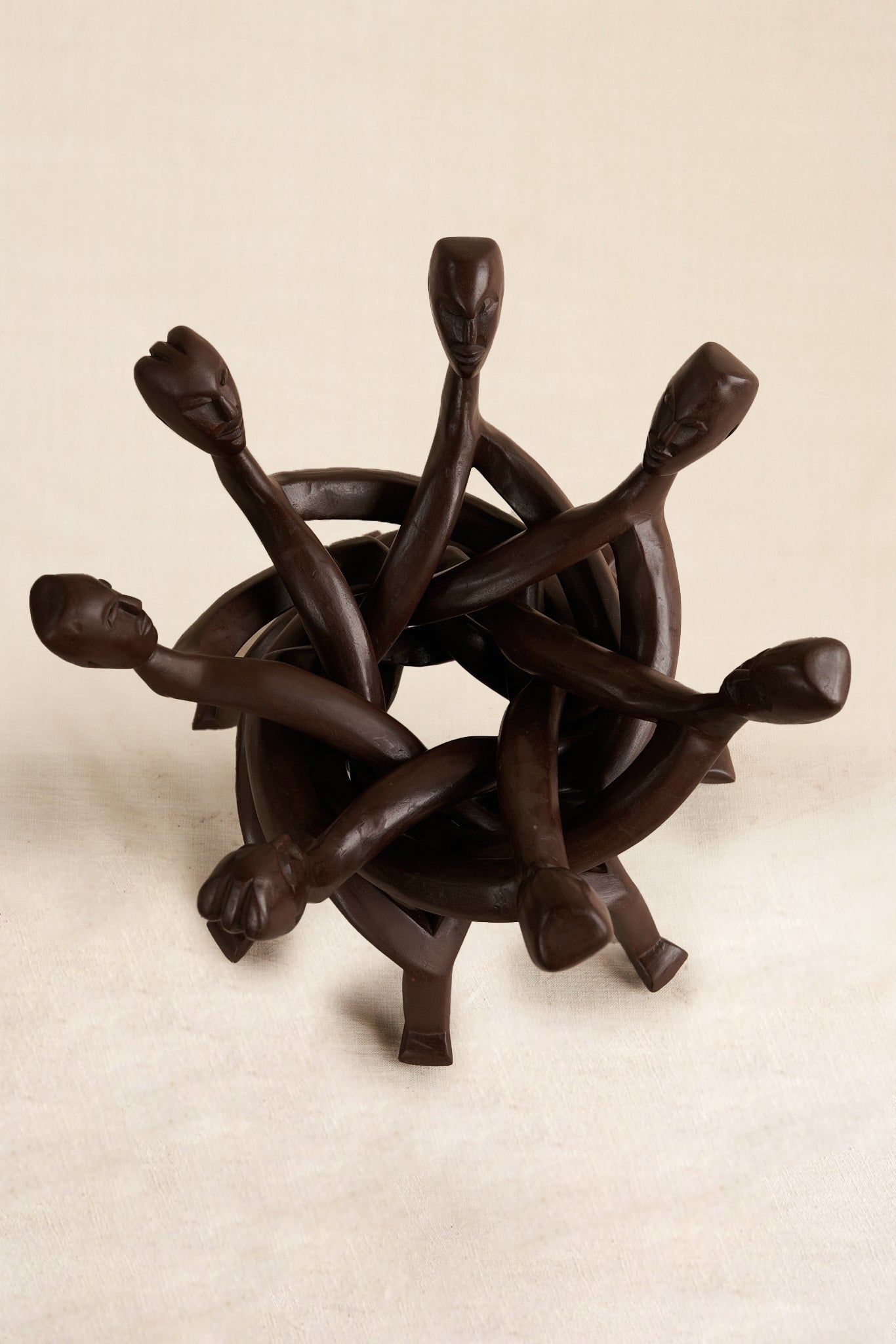 Wooden sculpture of interlocking figures on a beige background