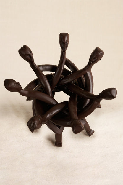 Wooden sculpture of interlocking figures on a beige background