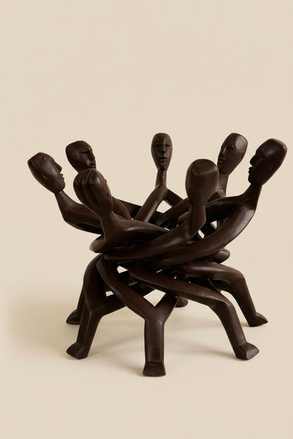 Wooden sculpture of interlocking figures on a beige background
