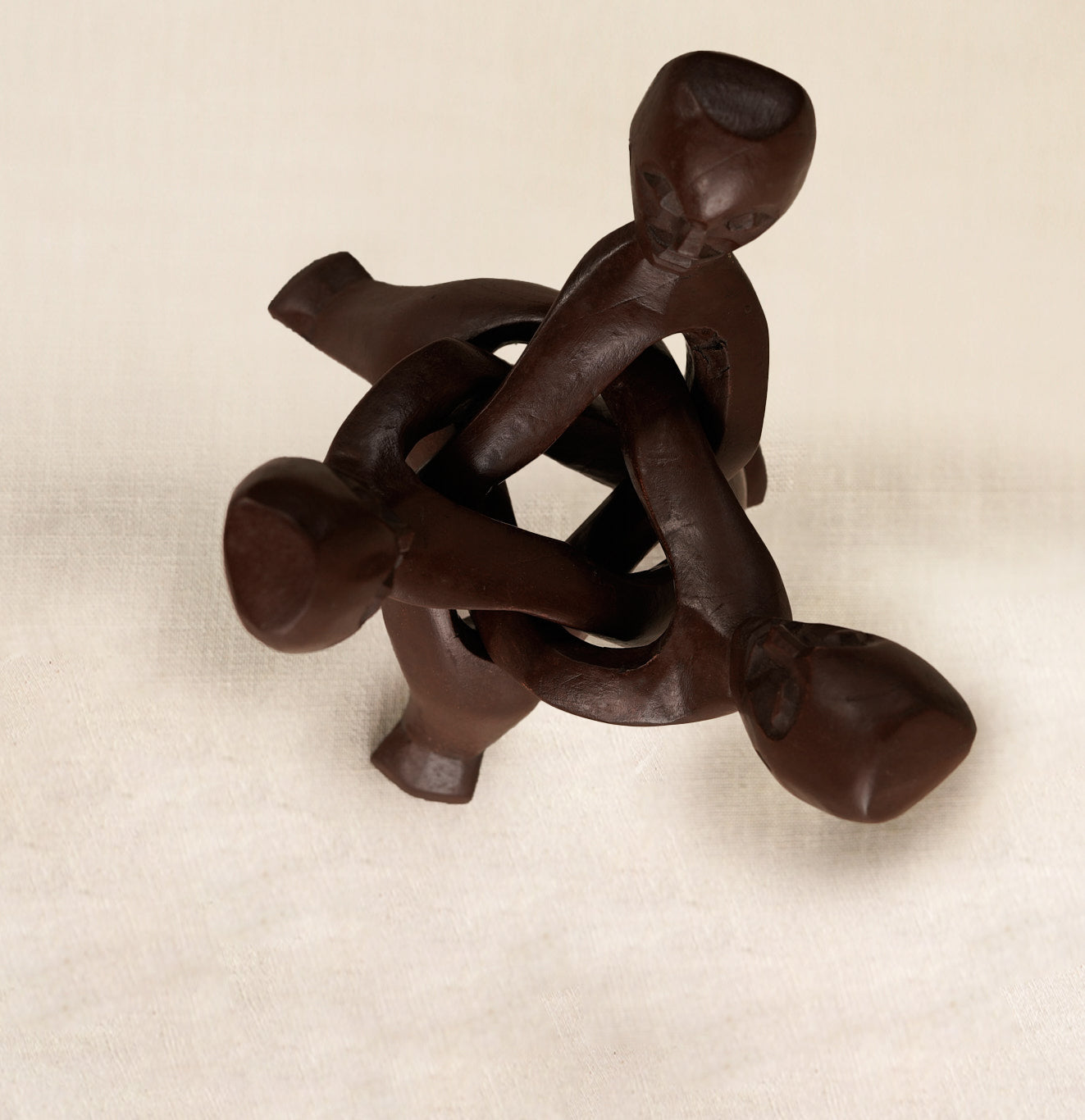 Wooden sculpture of interlocking figures on a beige background