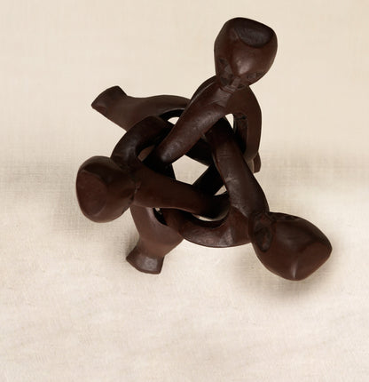 Wooden sculpture of interlocking figures on a beige background