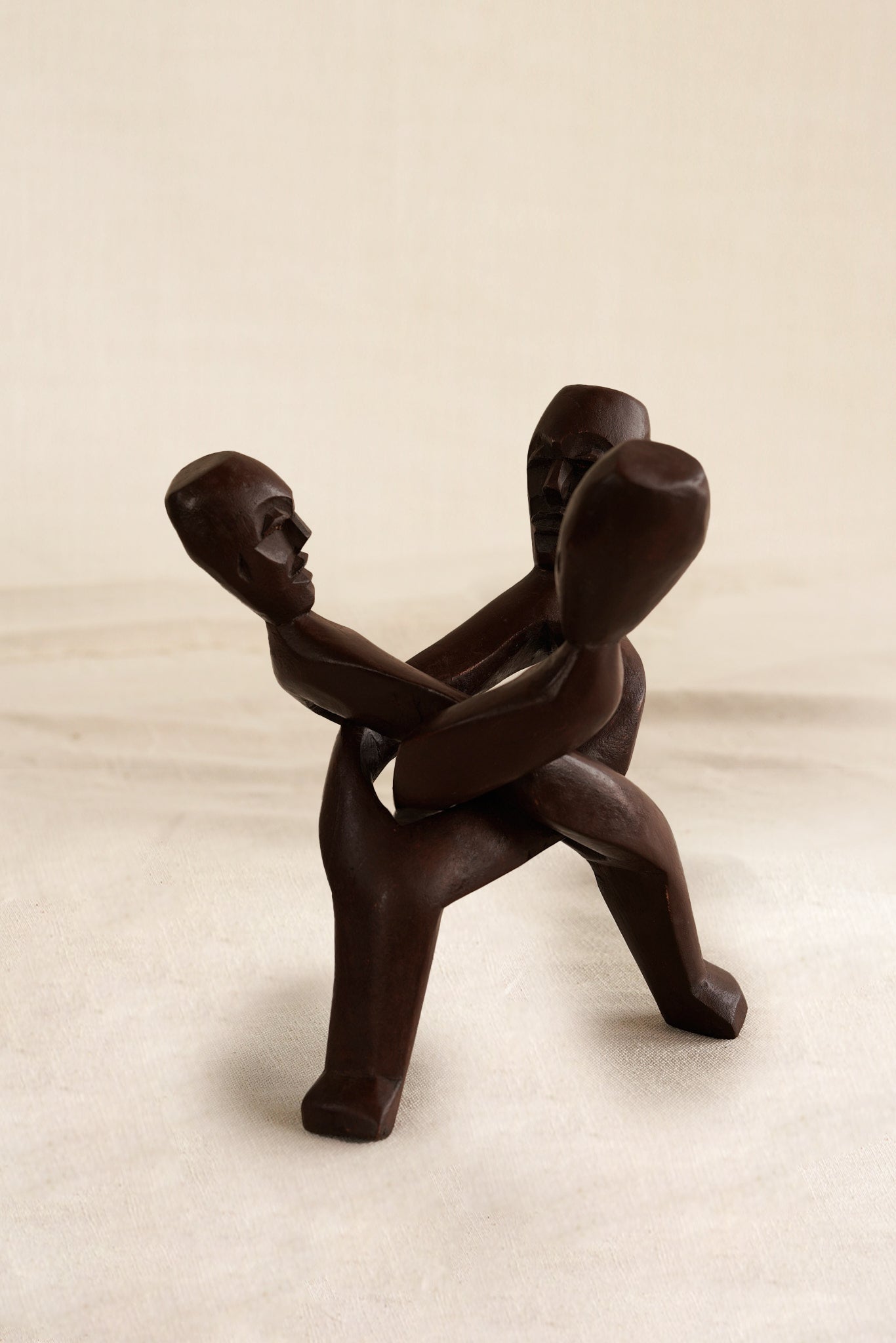 Wooden sculpture of interlocking figures on a beige background