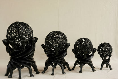 Four black decorative spheres on stands against a beige curtain background