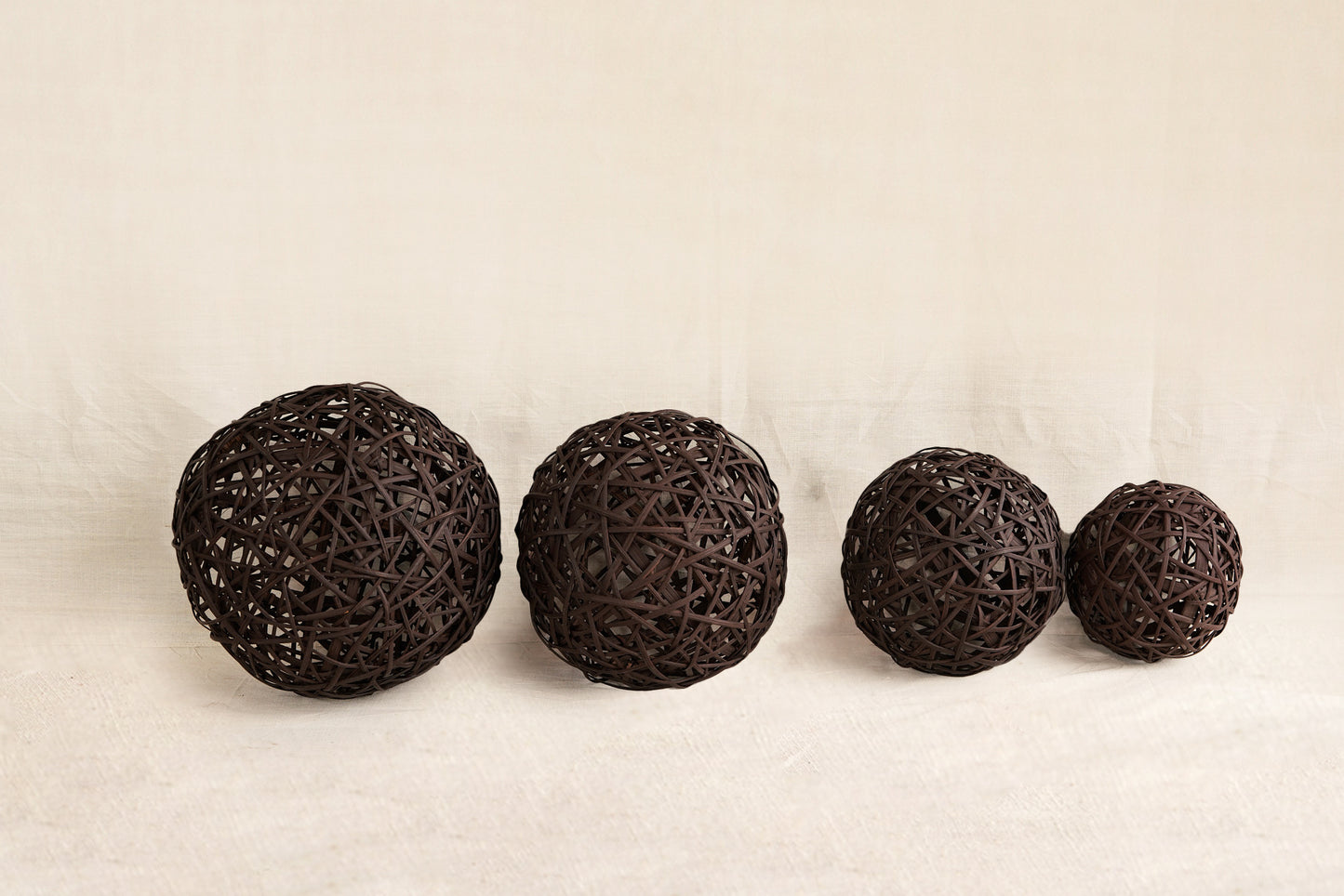 Four dark brown spherical objects on a beige background
