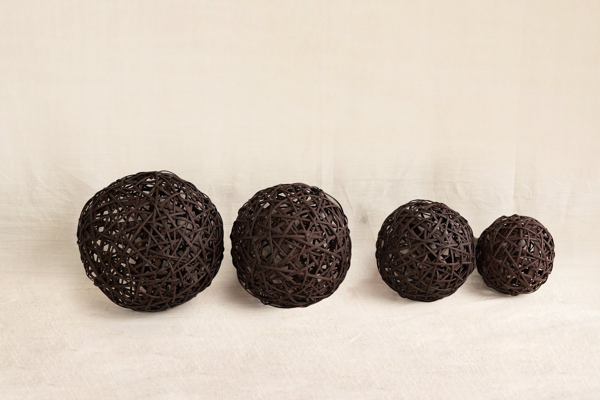 Four dark brown spherical objects on a beige background