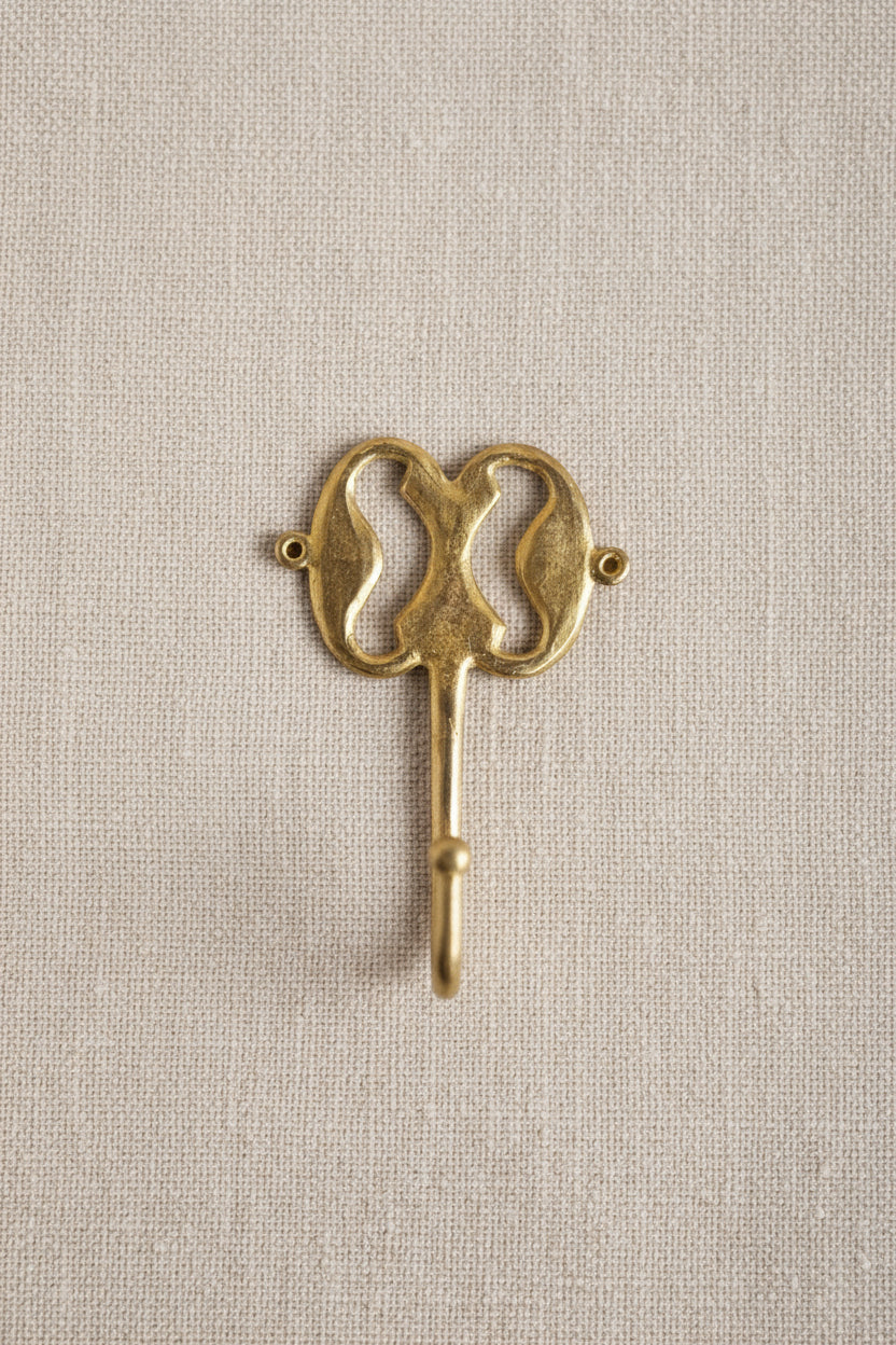 Brass decorative hook on a linen background