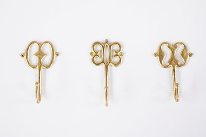 Set of brass decorative hooks on a white background
