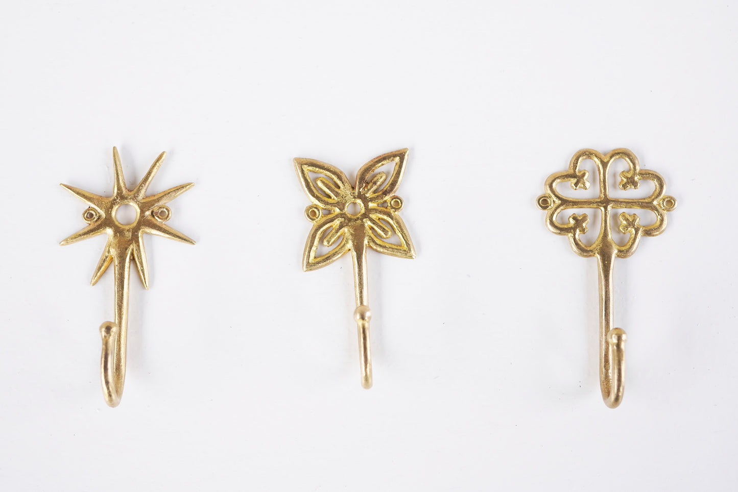 Set of brass decorative hooks on a white background