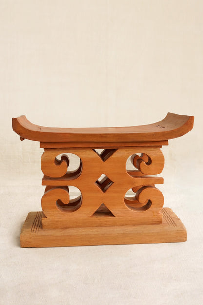 Wooden decorative stool with intricate carvings on a beige background