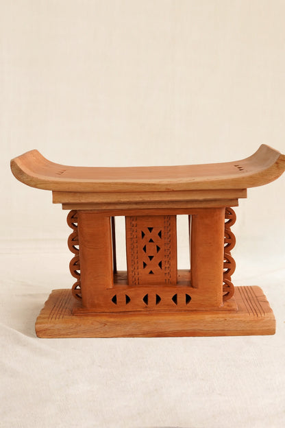 Wooden stool with intricate carvings on a beige background