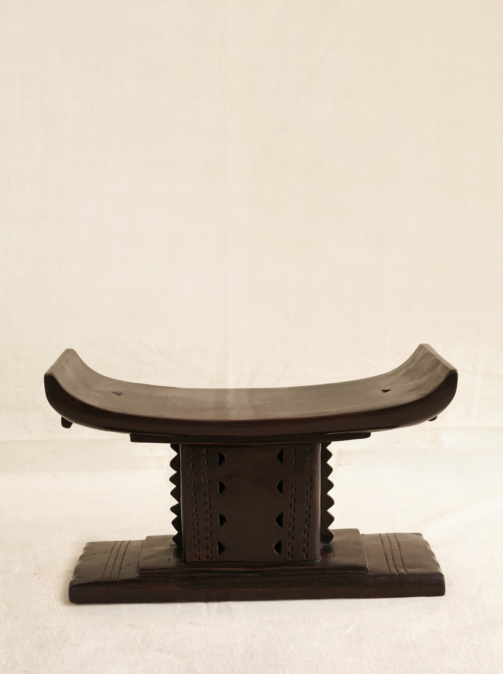 Wooden stool with curved backrest on a beige background