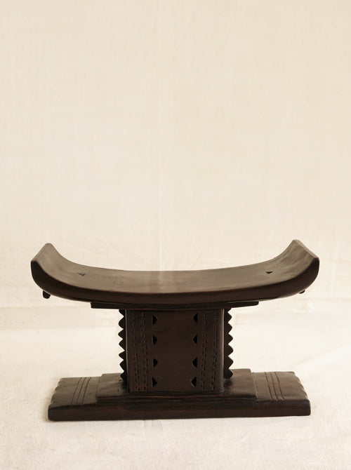 Wooden stool with curved backrest on a beige background