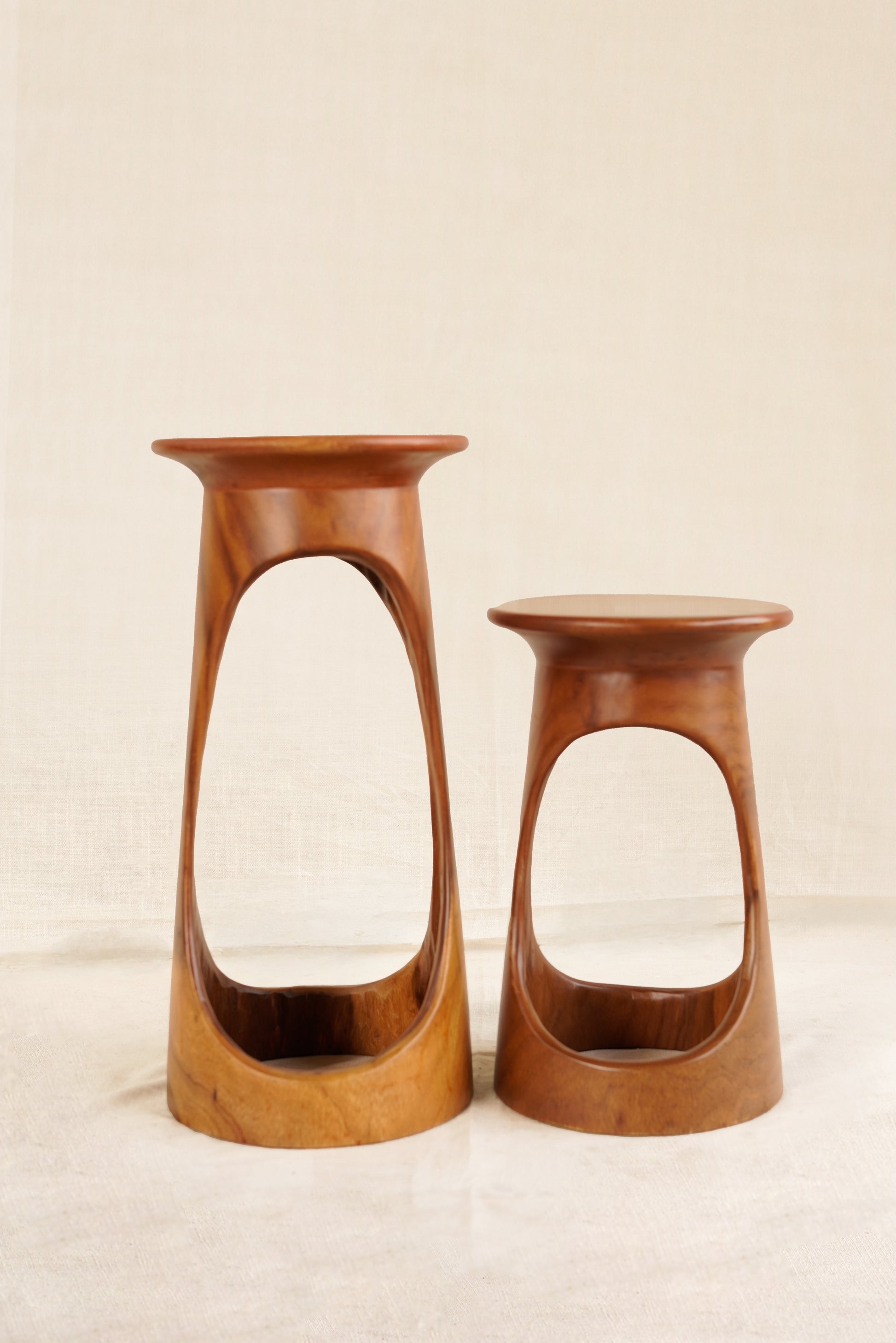 Two wooden stools with a modern design on a beige background
