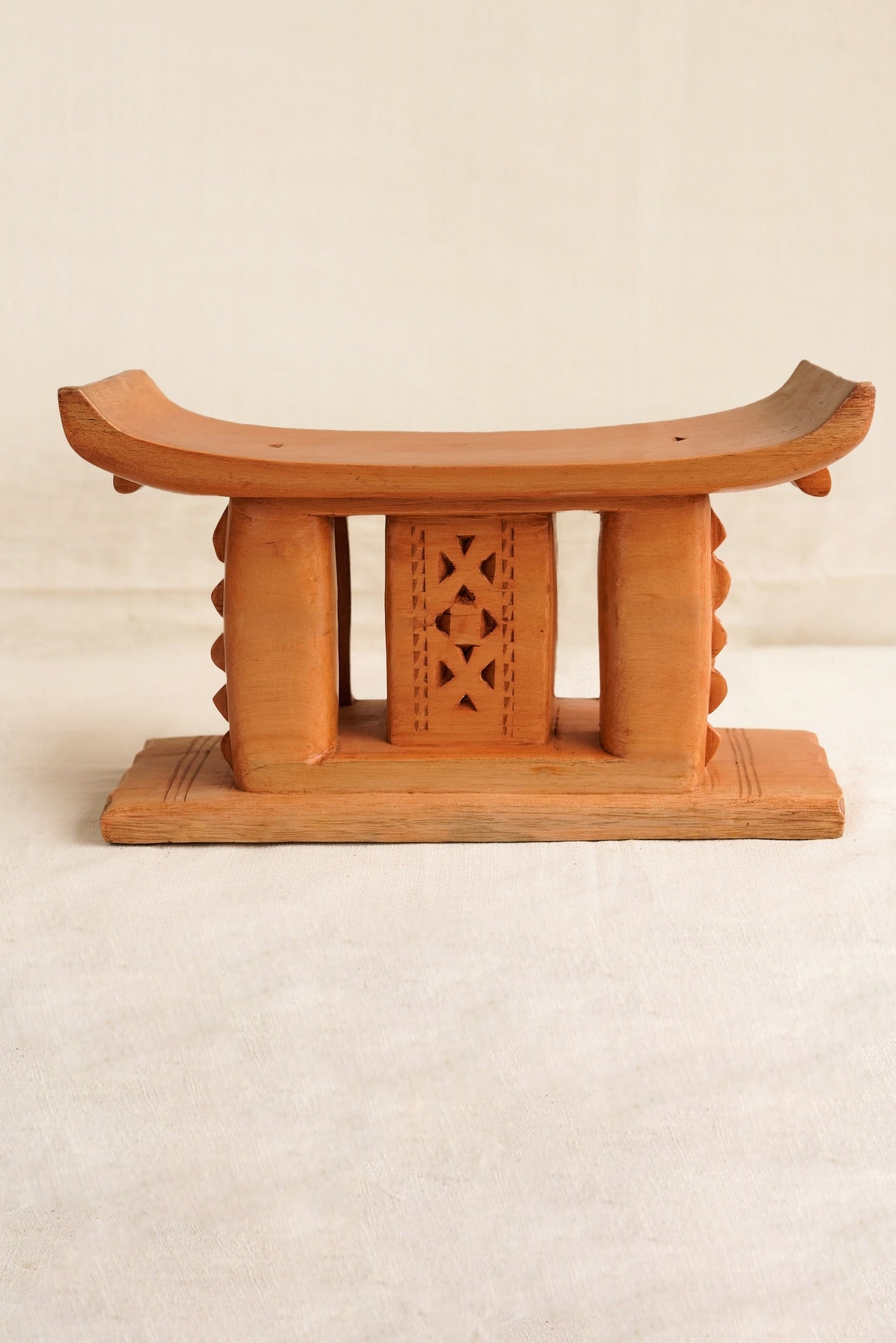 Wooden stool with decorative backrest on a beige background
