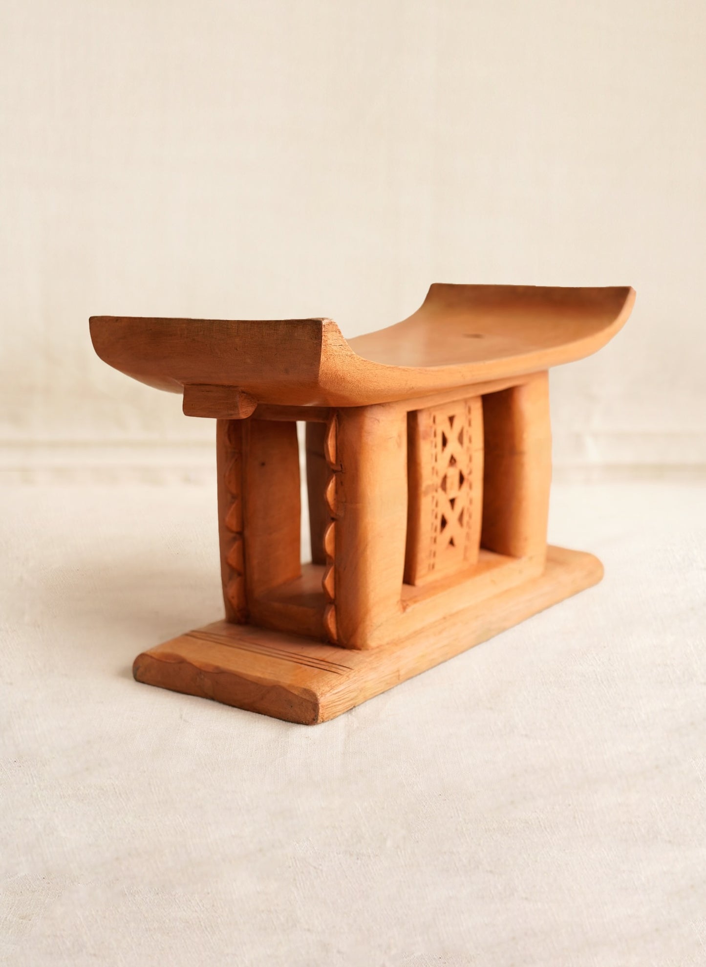 Wooden stool with intricate carvings on a beige background