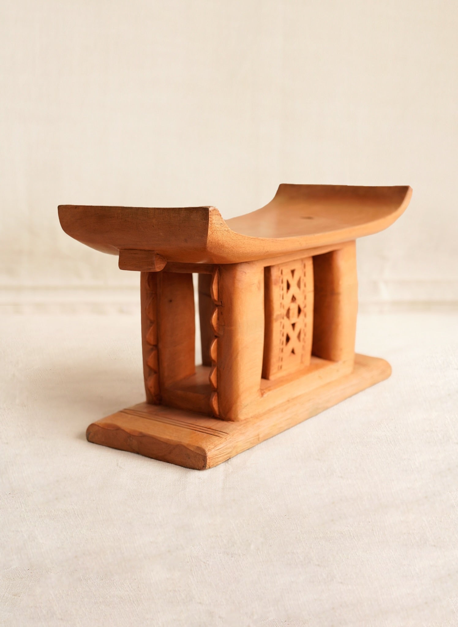 Wooden stool with intricate carvings on a beige background