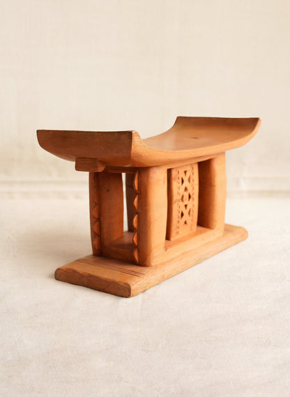 Wooden stool with intricate carvings on a beige background