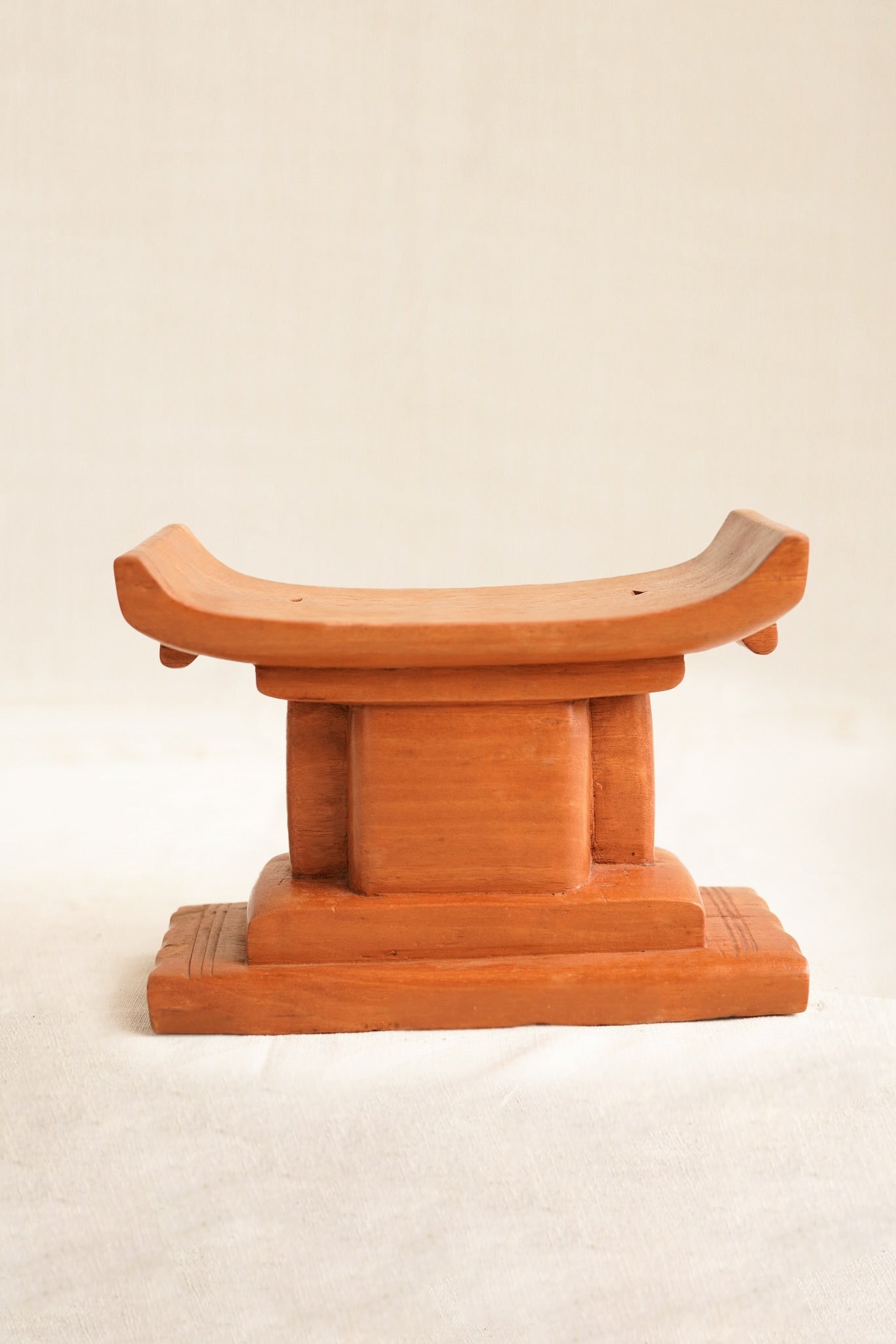 Wooden stool with curved top on a beige background