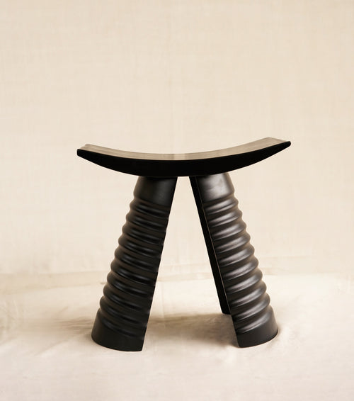 Black stool with unique design on a beige background