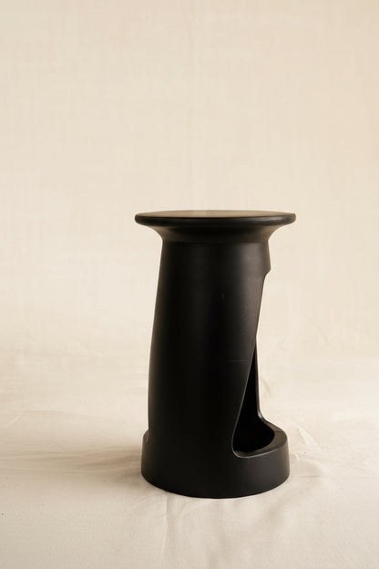 Black cylindrical stool on a beige background