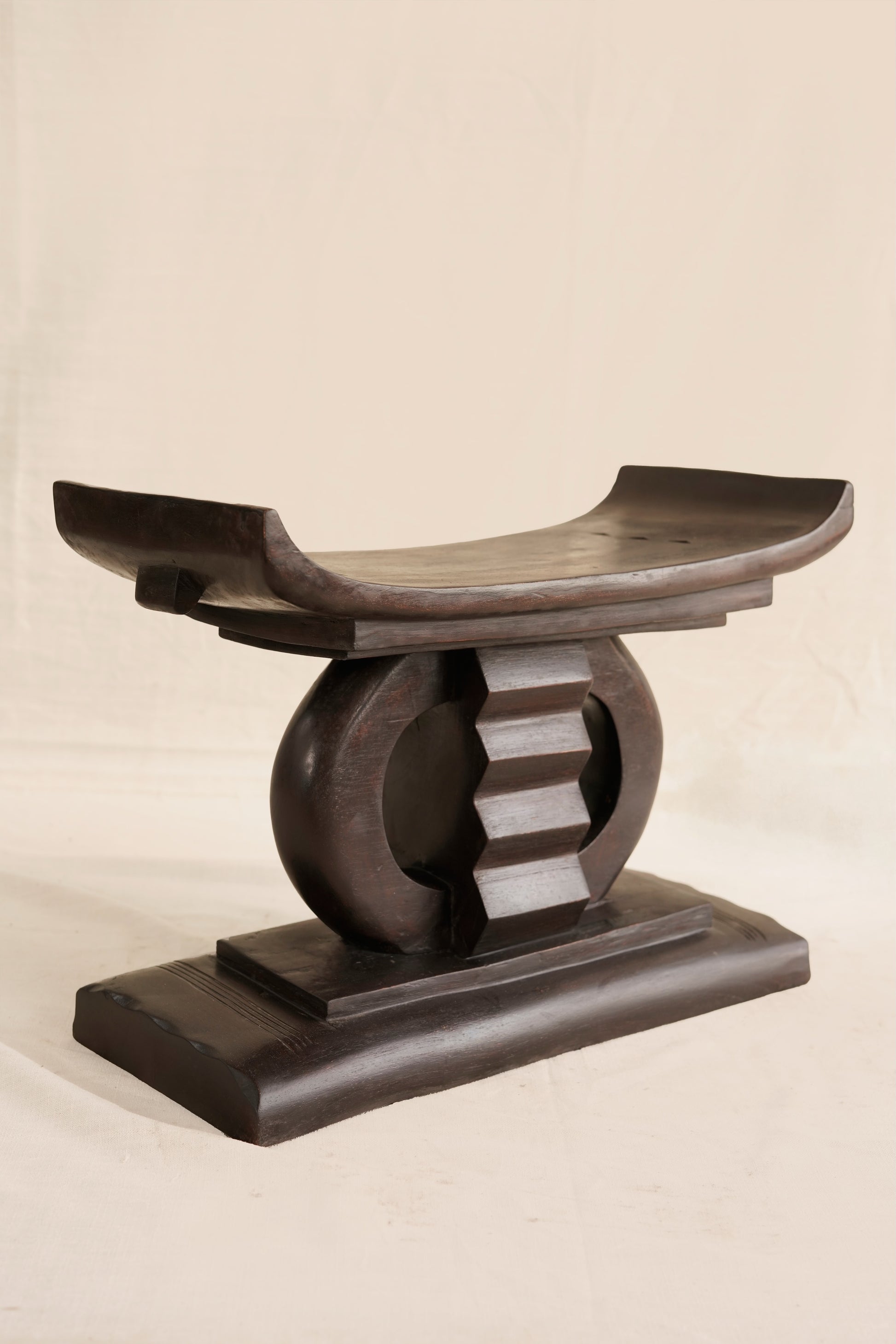 Wooden stool with curved design on a beige background