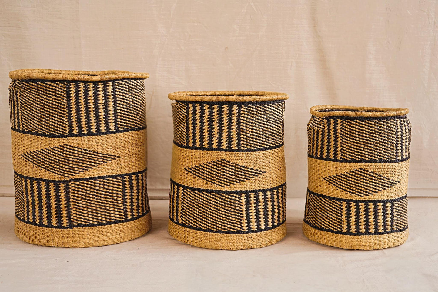 Three handwoven Bolga storage baskets in different sizes with geometric patterns, featuring complimentary linings.