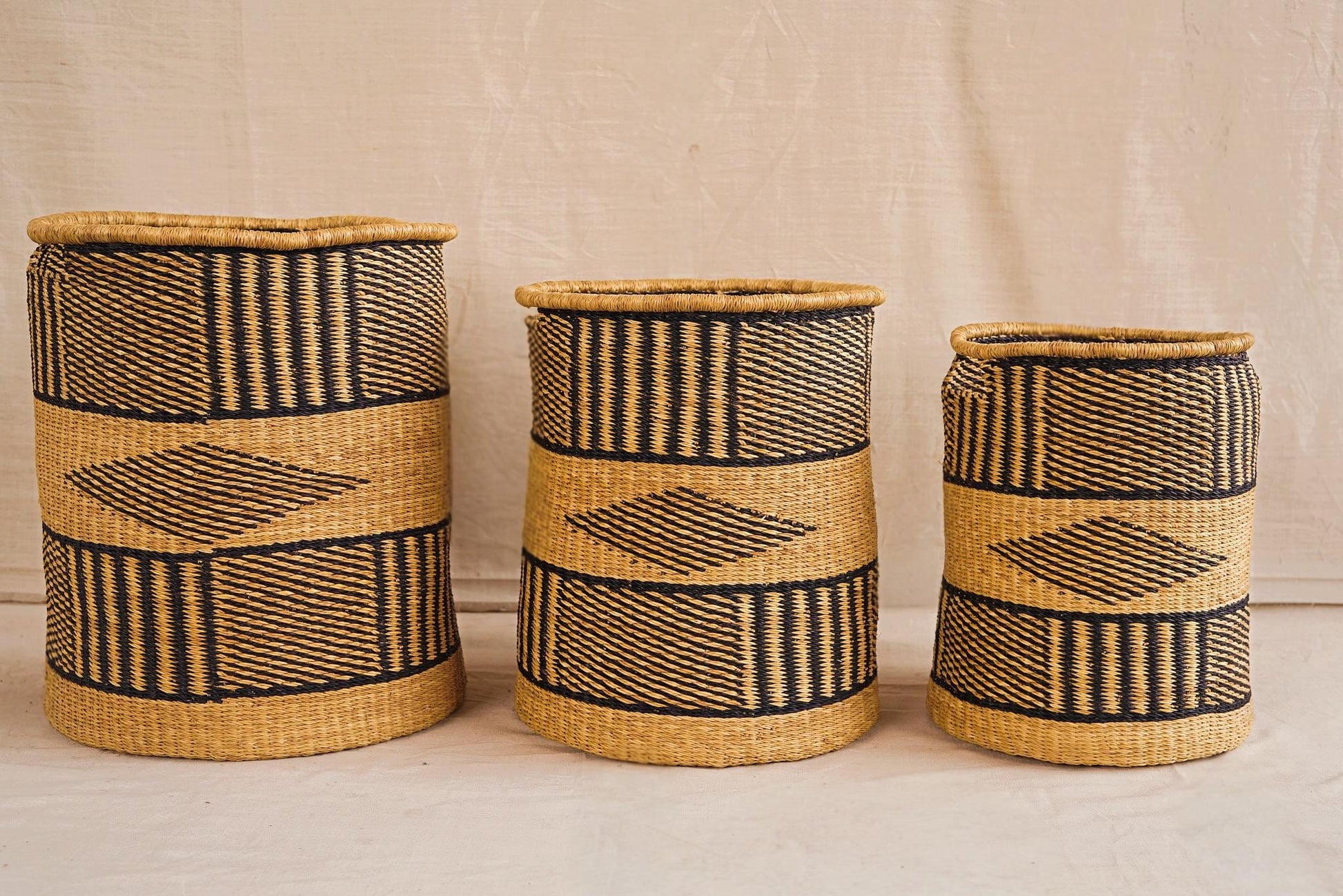 Three handwoven Bolga storage baskets in different sizes with geometric patterns, featuring complimentary linings.