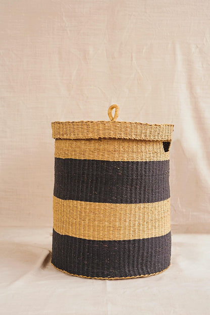 Woven basket with black and natural stripes on a plain background