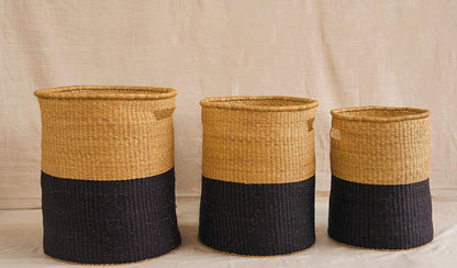 Three woven baskets with black and natural yellow design on a plain background.