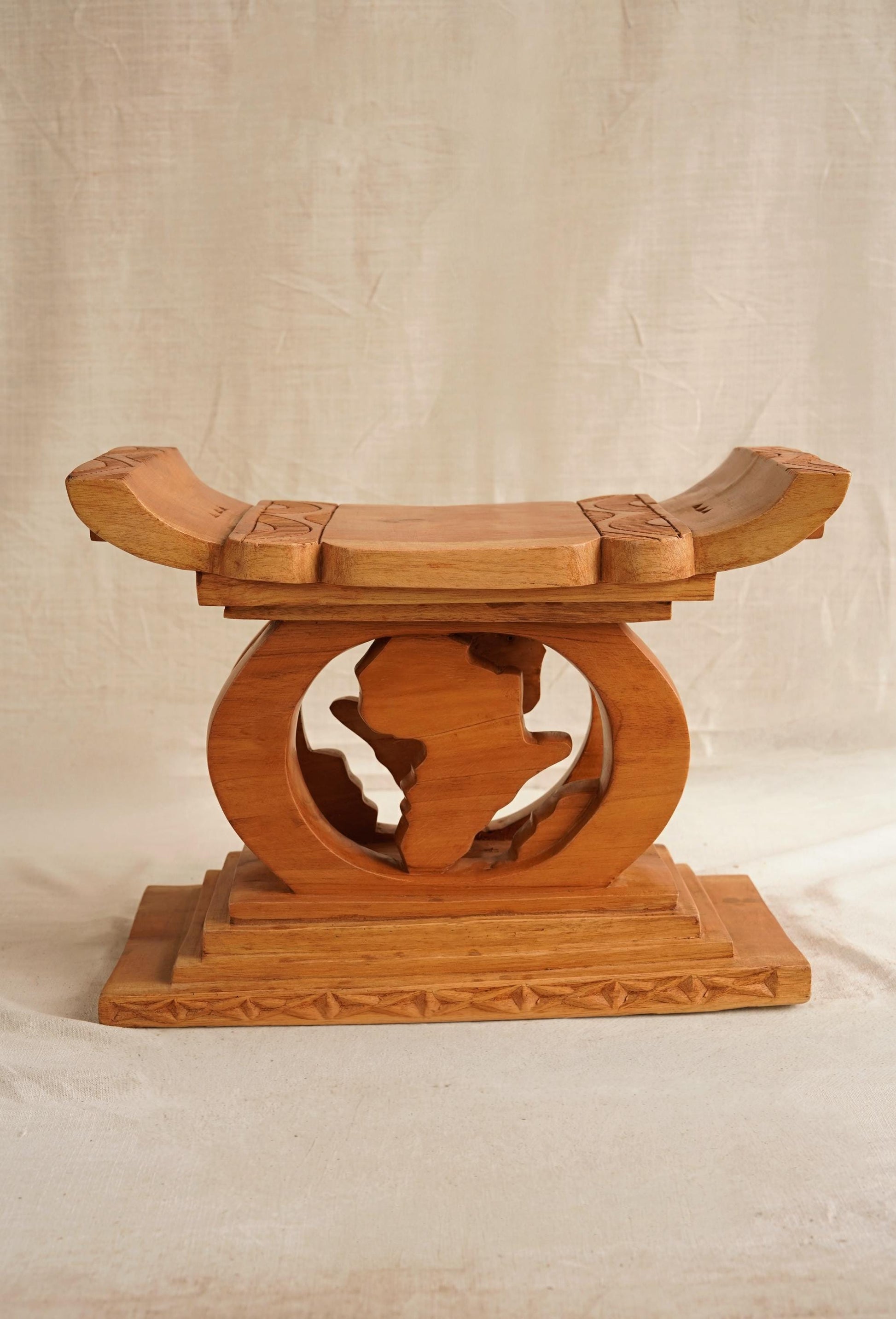 A hand-carved wooden Ashanti stool from Ghana, with a curved seat and arched base, featuring detailed motifs. Map of Africa Ashanti Stool