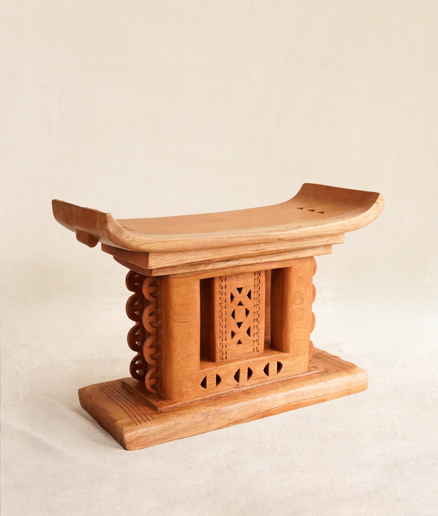 Wooden stool with intricate carvings on a beige background