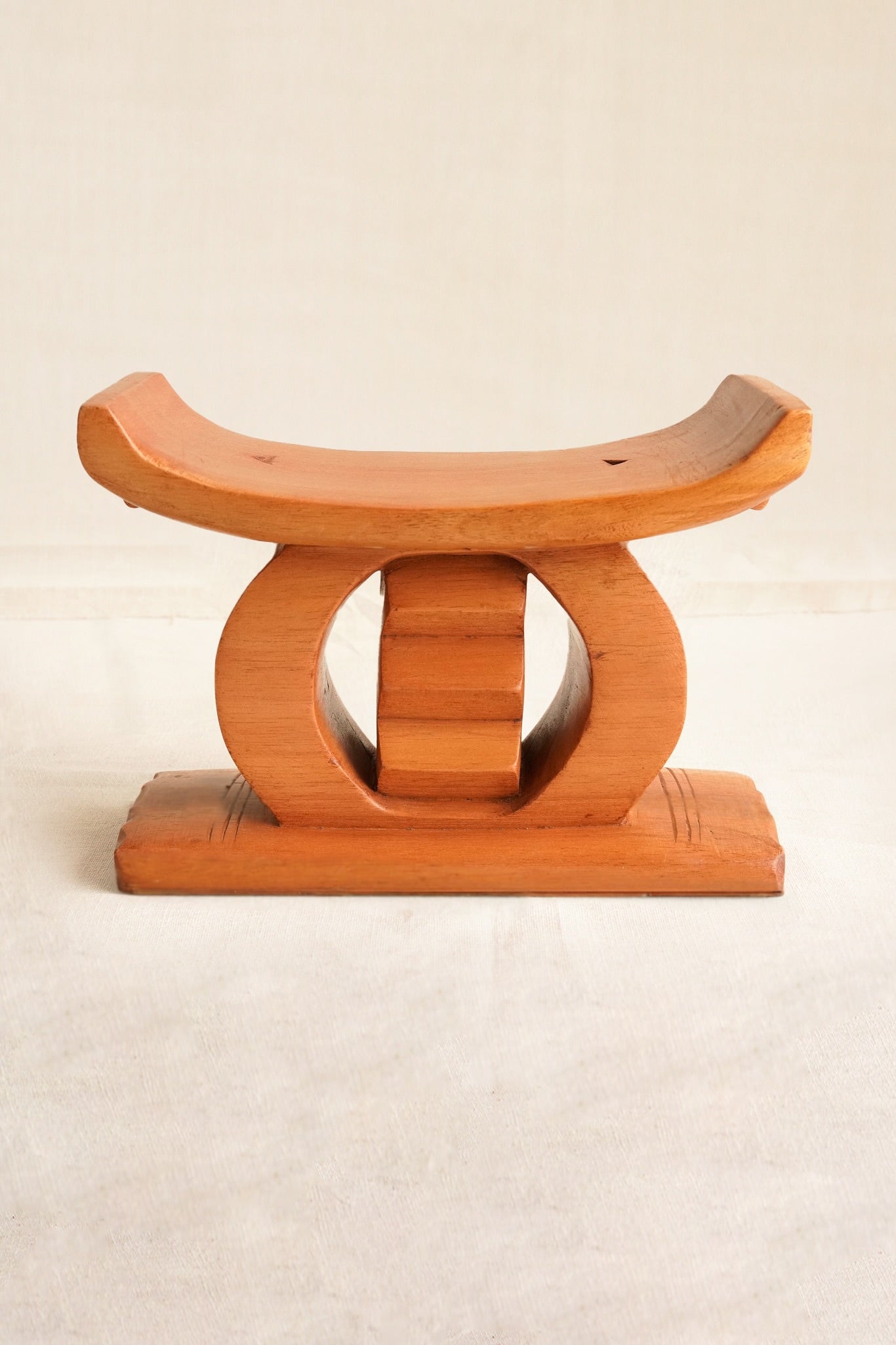 Wooden stool with curved design on a beige background