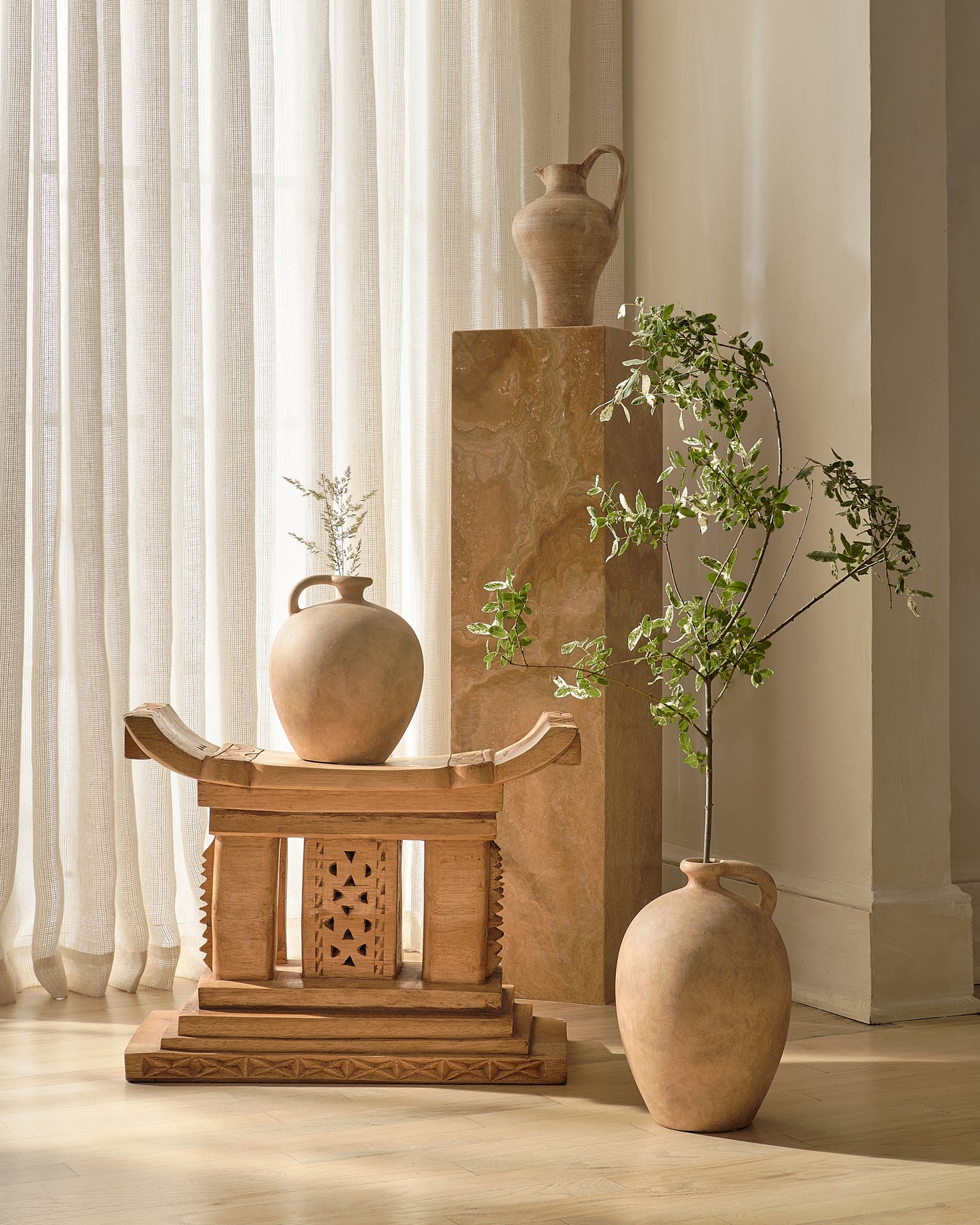 Decorative Natural Ashanti stool  on a beige background stagger with 3 Pots, a pedestal and a branch 