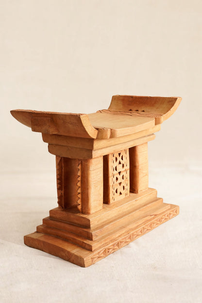 Wooden stool with intricate carvings on a beige background