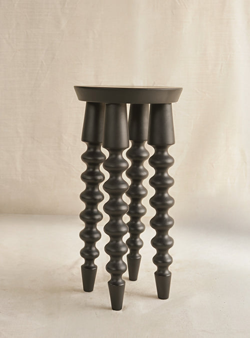 Dark wooden stool with spiral design legs on a beige background