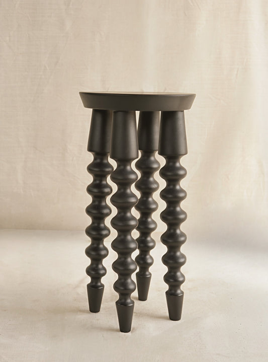 Dark wooden stool with spiral design legs on a beige background
